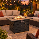Propane fire pit table burning on a backyard patio at dusk